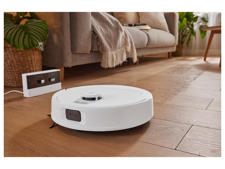 Ein Roboterstaubsauger auf einem Holzboden im Wohnzimmer.