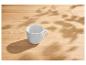 Eine leere weiße Tasse auf einem Holztisch mit Blattschatten.