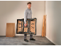 Mann trägt eine klappbare Werkbank in einem Raum mit Holzbrettern.