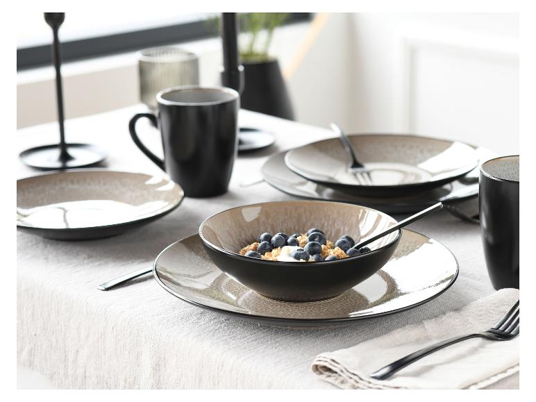 Gedeckter Tisch mit schwarzen Schalen und Tassen, eine Schale mit Müsli und Blaubeeren.