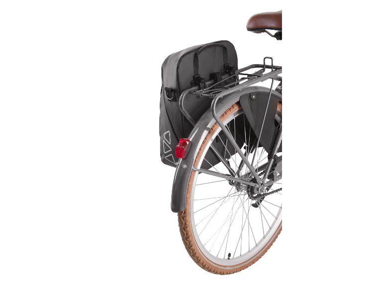 Schwarze hintere Fahrradtaschen an einem Fahrradgepäckträger mit braunem Reifen.