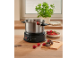 Schokoladenfondue-Set mit Erdbeeren und Schokoladenstücken auf einem Holztisch.