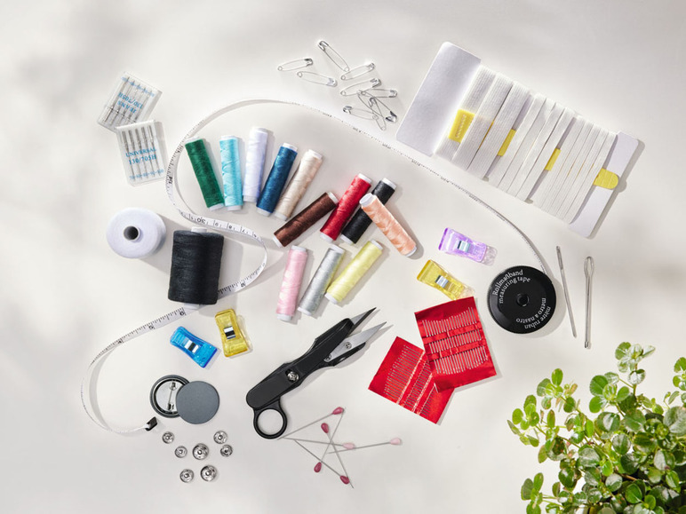 Nähzubehör, darunter Garn, Nadeln, Knöpfe und ein Maßband.