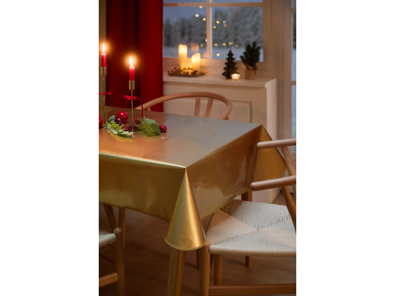 Festlicher Esstisch mit goldener Tischdecke, roten Kerzen und Weihnachtsdekorationen.