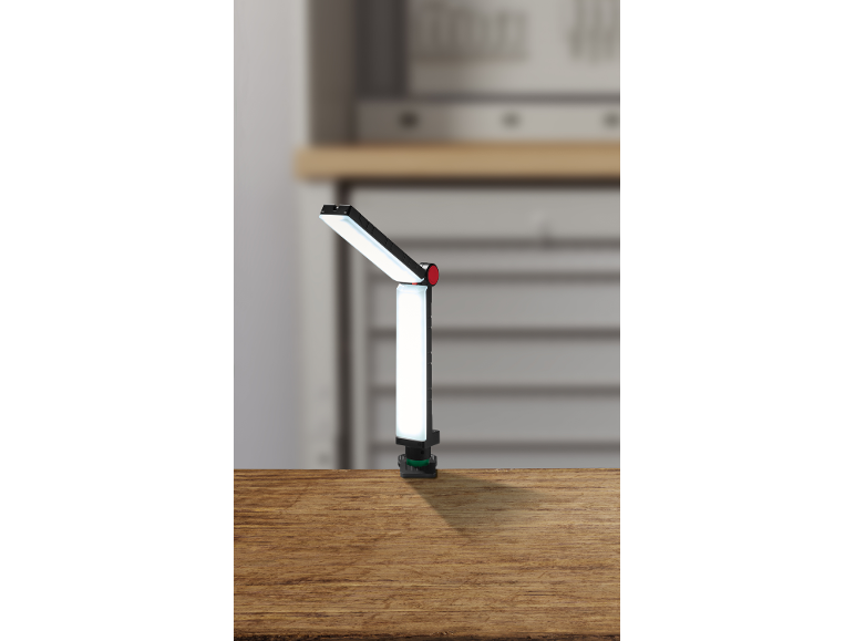 Verstellbare LED-Arbeitsleuchte mit Klemme auf einer Holzoberfläche in einer Werkstattumgebung.