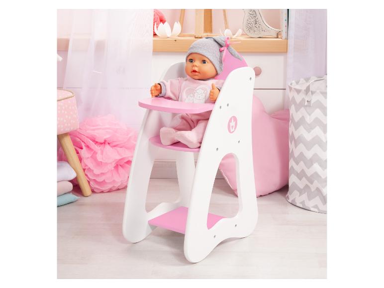Babypuppe sitzt in einem weißen und rosa Holzhochstuhl in einem Kinderzimmer.