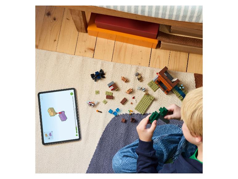 Kind baut LEGO Minecraft mit digitaler Anleitung auf einem Tablet.