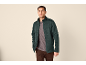 Mann in dunkelgrüner Fleecejacke, grauem T-Shirt und brauner Hose.