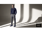Mann in dunkelblauem Pullover, grauer Hose und blauen Wildlederstiefeln.