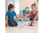Zwei Kinder spielen mit einem weiß-blauen Roboterwelpen auf dem Boden.