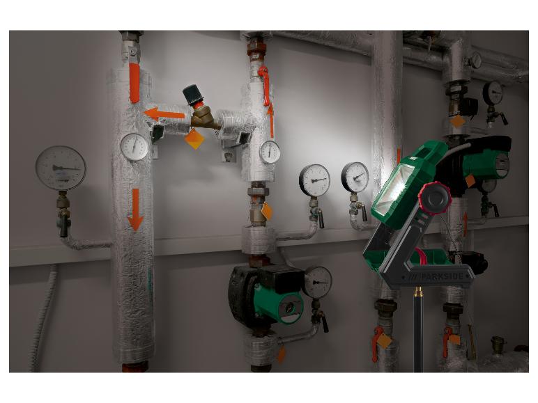 Tragbare LED-Arbeitsleuchte beleuchtet Rohre und Manometer in einem Heizraum.