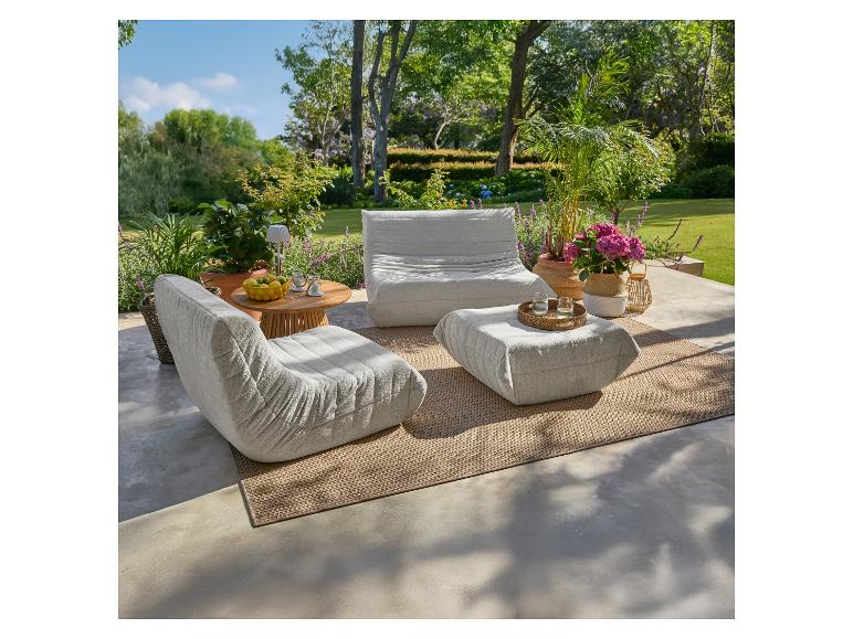 Outdoor-Lounge-Set mit zwei Sesseln, einem Hocker und einem Beistelltisch auf einer Terrasse.