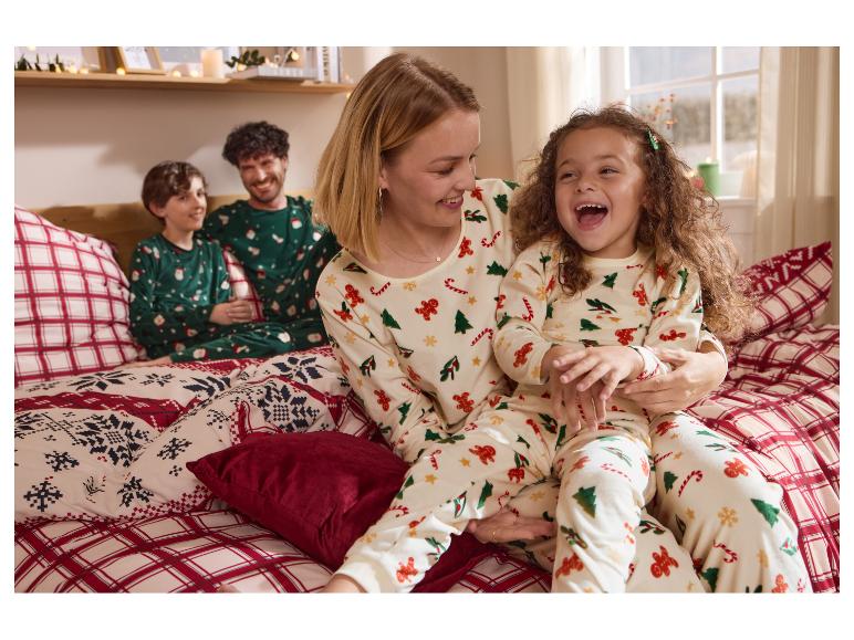 Familie in passenden Weihnachtspyjamas und weihnachtlicher Bettwäsche