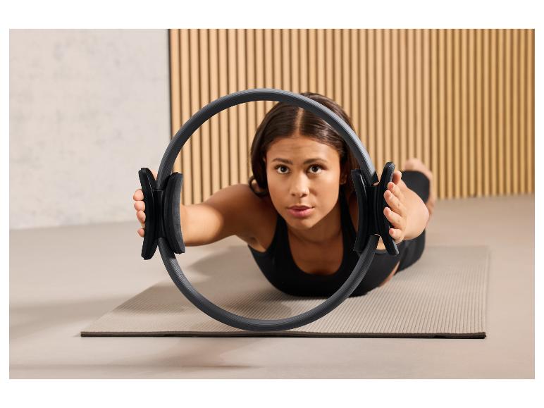 Eine Frau macht Pilatesübungen mit einem Pilatesring auf einer Matte.