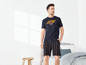 Mann in einem schwarzen T-Shirt mit 'Sundown'-Aufdruck und gestreiften Pyjama-Shorts.