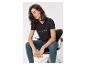 Frau in schwarzem T-Shirt mit Schriftzug und Jeans, auf einem Stuhl sitzend.