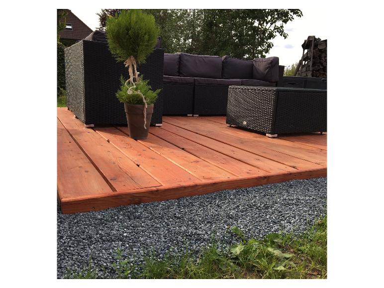 Terrasse mit Holzdeck, dunkler Rattan-Sitzgruppe und einer kleinen Topfpflanze.