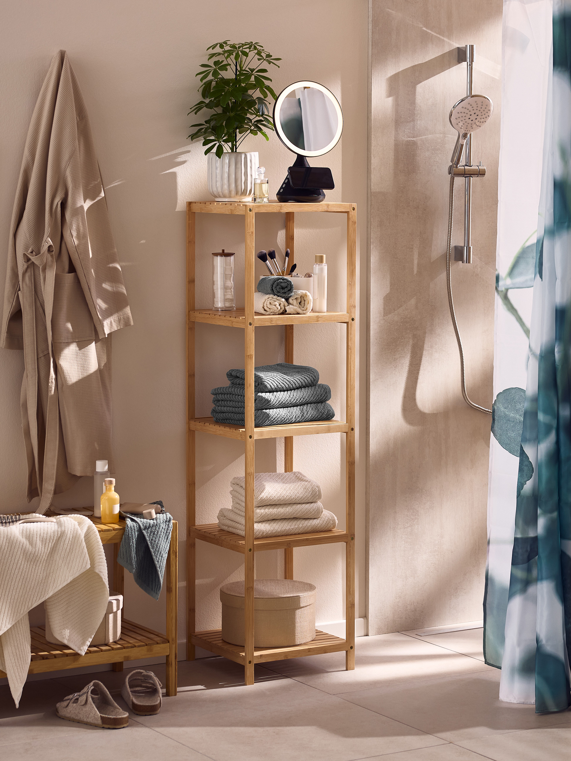 Badezimmer mit Bambusregal, Bademänteln, Handtüchern und Dusche.