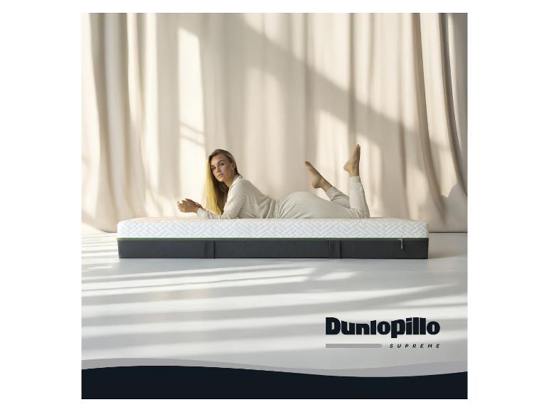 Frau auf einer Dunlopillo Supreme Matratze, mit beigen Vorhängen im Hintergrund.