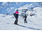 Zwei Skifahrer in Skijacken und Skihosen auf dem verschneiten Berg.