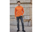Ein Mann trägt einen orangefarbenen Pullover und graue Jeans.
