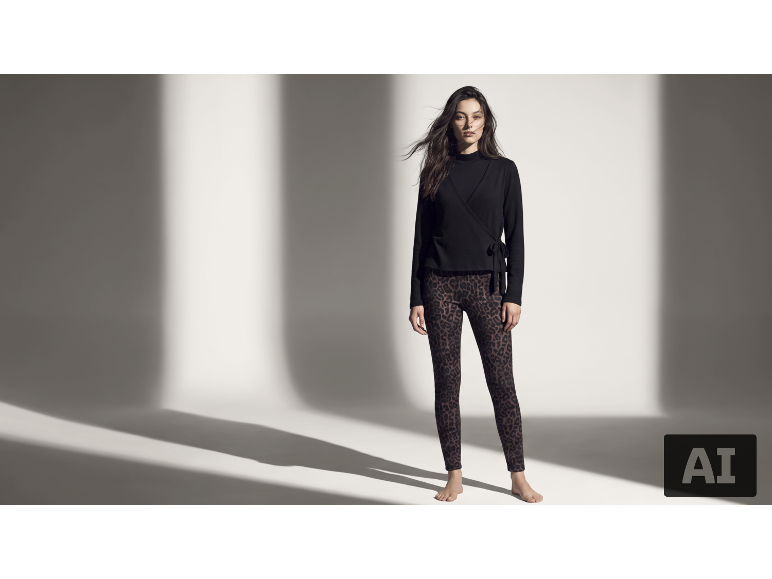 Eine Frau in einem schwarzen Wickeltop und Leggings mit Leopardenmuster vor weißem Hintergrund.