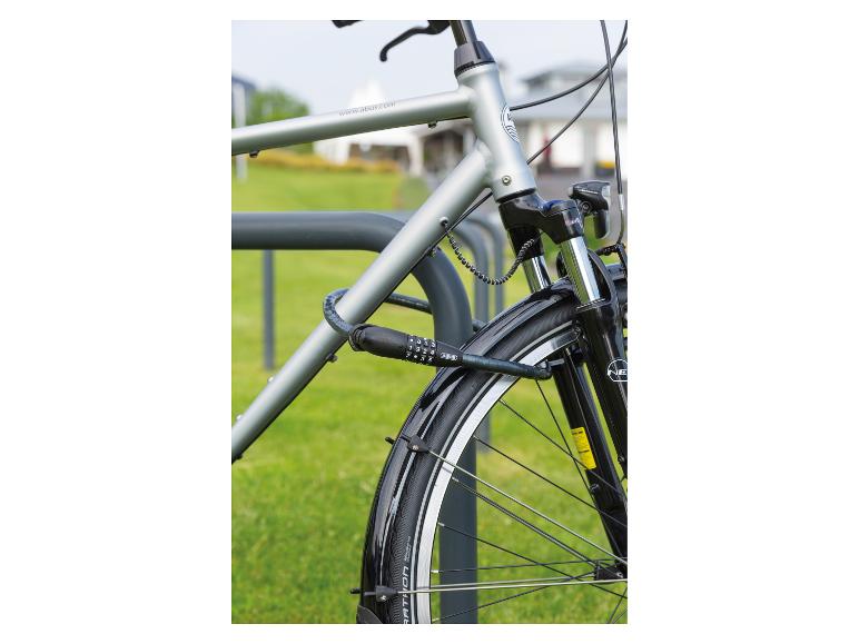 Stadtrad mit Zahlenschloss, an einem Fahrradständer auf einer Wiese gesichert.