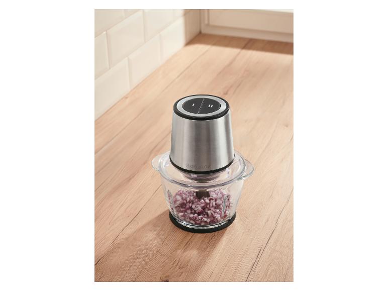 Silberner Zerkleinerer mit gehackten roten Zwiebeln auf einer Holztheke.