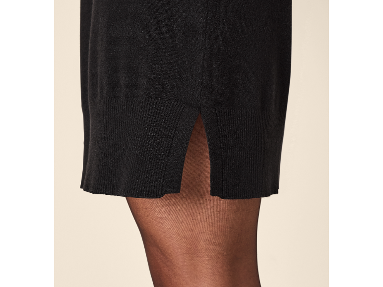 Schwarzes Strickkleid mit Schlitz und schwarze Strumpfhose.