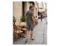 Mann in grünem T-Shirt mit Palmenaufdruck und grauen Shorts geht eine Straße entlang.