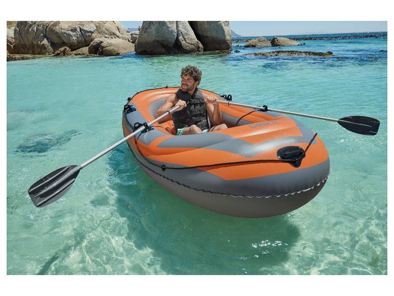 Ein Mann rudert in einem CRIVIT Schlauchboot in klarem Wasser.