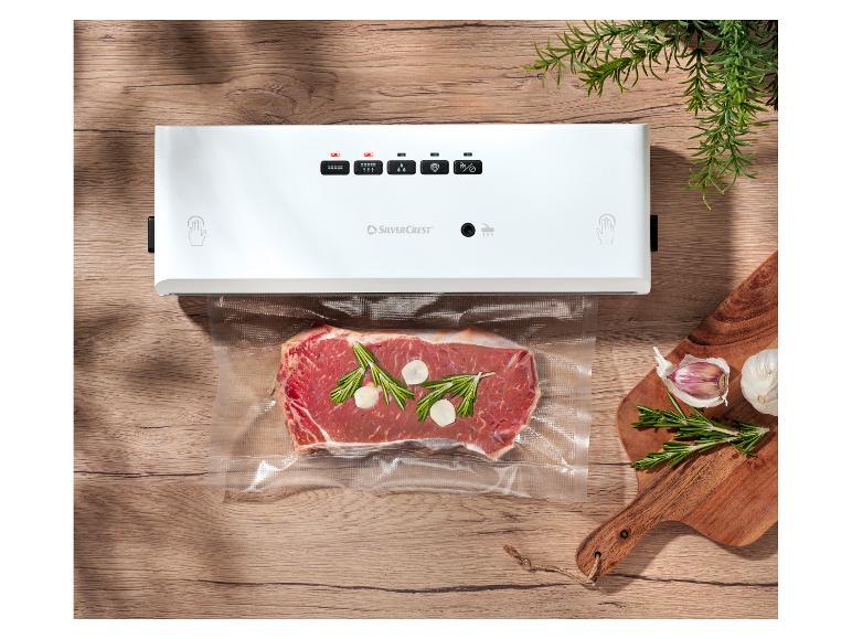 SilverCrest Vakuumierer mit Steak, Rosmarin und Knoblauch auf einem Holztisch.