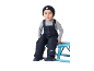 Junge in dunkelblauem Overall und Strickmütze sitzt auf einer blauen Bank.