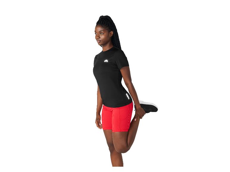 Frau in schwarzem Sportshirt und roten Shorts dehnt ihr Bein.