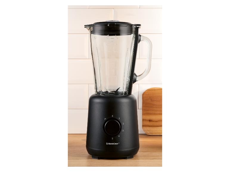 Schwarzer Mixer mit Glaskrug, Drehregler und Messmarkierungen auf einer Holzoberfläche.