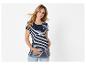 Lächelnde schwangere Frau in gestreiftem Umstandstop und Jeans, die ihren Bauch hält.