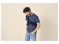 Mann in blauem T-Shirt, dunkelblauem Pullover um die Schultern gebunden und heller Jeans.