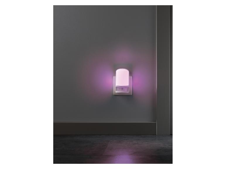 Steckdosen-Nachtlicht mit sanftem violettem Schein an einer grauen Wand.