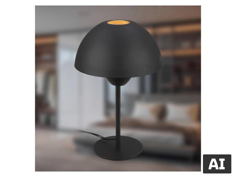 Schwarze Tischlampe mit kuppelförmigem Schirm, rundem Fuß und Kabel, auf verschwommenem Hintergrund.