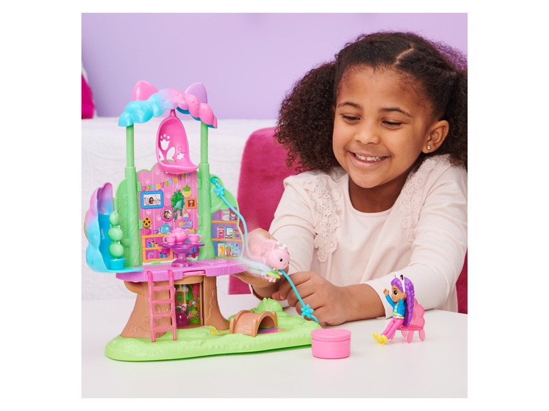 Ein Mädchen spielt mit einem Spielset mit Baumhaus und Puppen