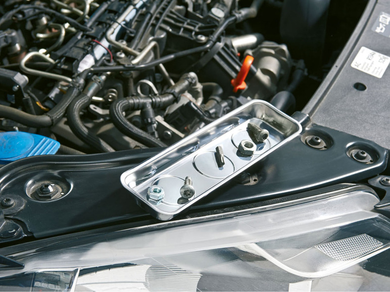 Schrauben und Muttern in einer magnetischen Schale bei der Autoreparatur.