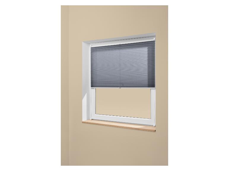 Graues Plissee an einem weißen Fenster mit einer Holzfensterbank.