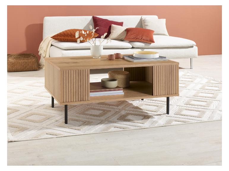 Heller Holz-Couchtisch mit Ablagen, auf einem hellen Teppich vor einer hellen Couch.