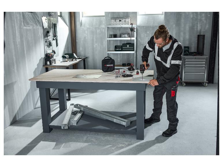 Mann in PARKSIDE PERFORMANCE® Warnschutz-Sweatjacke bohrt in einer Werkstatt.