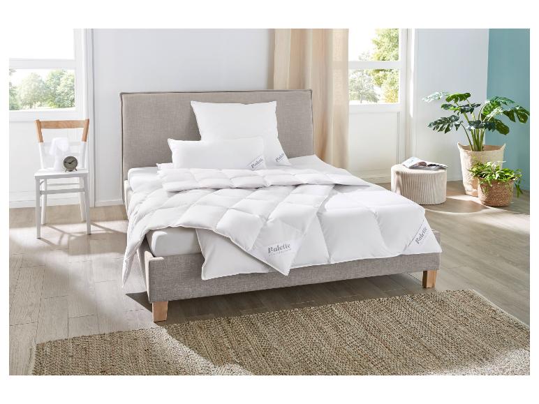Weiße Balette Bettdecke und Kissen auf einem gepolsterten Bett in einem Schlafzimmer mit Pflanzen.