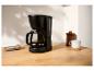 Schwarze Filterkaffeemaschine mit Glaskanne, Tasse und Keksen auf einem Holztisch.