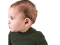 Nahaufnahme eines Babys in einem grünen Strickpullover, das nach links schaut.