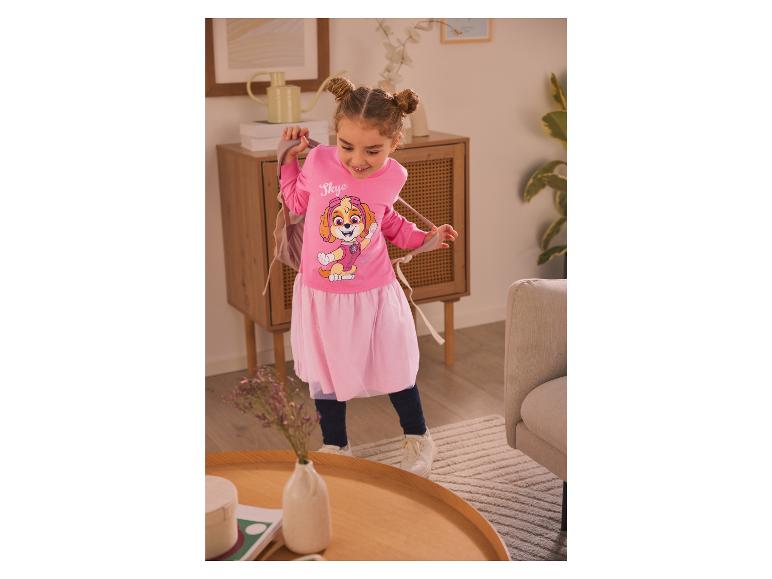 Ein Mädchen trägt ein rosafarbenes Kleid mit Skye von Paw Patrol.