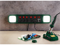 Steckdosenleiste mit LED-Leuchten und Lötkolben auf einer Werkbank mit Platine.
