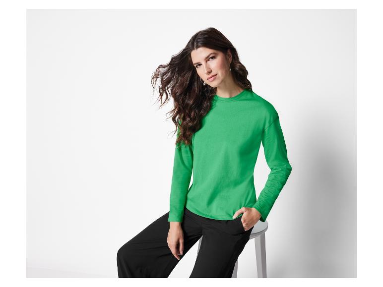 Frau in einem grünen Langarmshirt und schwarzen Hosen